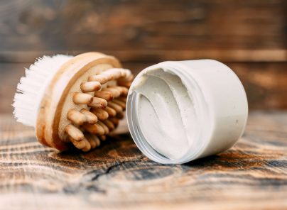 Naturkosmetik und Massagebürste auf Holzuntergrund für Wohlbefinden und Pflege.