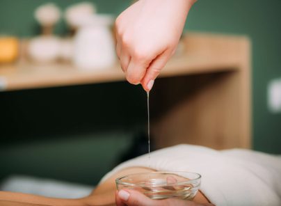 Massageöl wird aus einer Schale in die Hand gegossen für eine entspannende Behandlung.