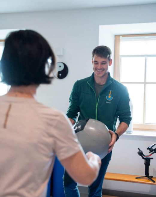 Therapeut räumt mit einem Gymnastikball in einem modernen Gesundheitszentrum auf.