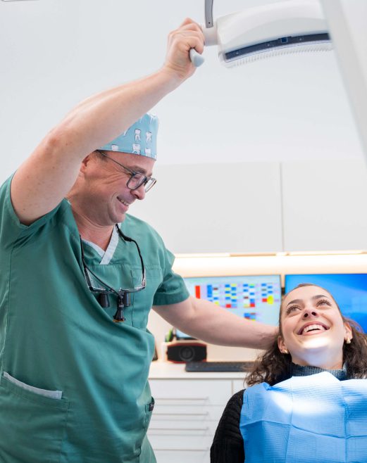 Zahnarzt behandelt lächelnde Patientin in moderner Praxisumgebung.