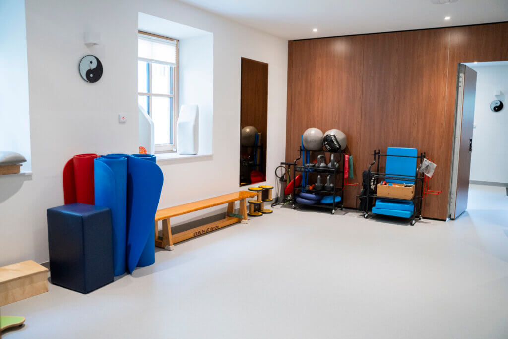 Therapieraum mit Sportgeräten, Matten und Holzbank im Gesundheitszentrum Radstadt.