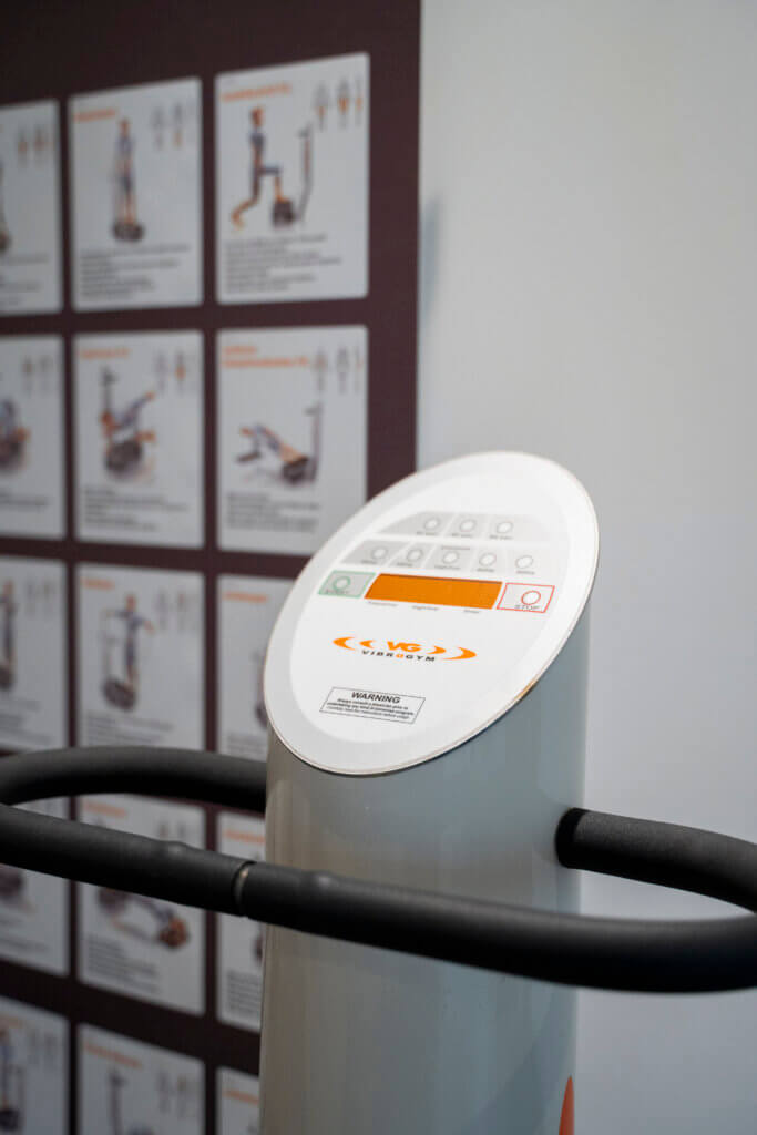 Vibrationsgerät in einem Gesundheitszentrum mit Anleitungen im Hintergrund.