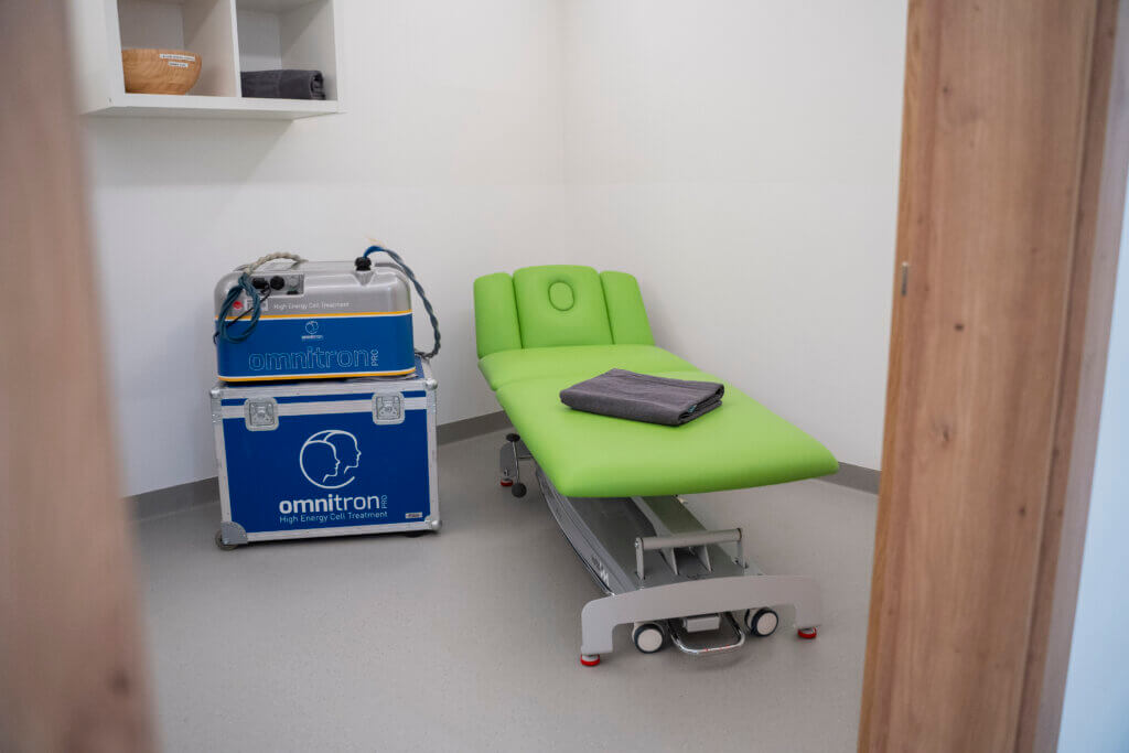 Therapieraum im Gesundheitszentrum Radstadt mit grünem Behandlungsstuhl und medizinischem Gerät.