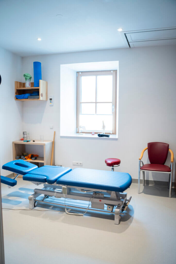 Behandlungsraum im Gesundheitszentrum Radstadt mit Therapieliege und Stuhl.
