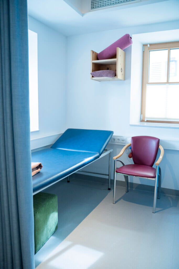 Behandlungsraum im Gesundheitszentrum Radstadt mit Liege, Stuhl und Rollläden.
