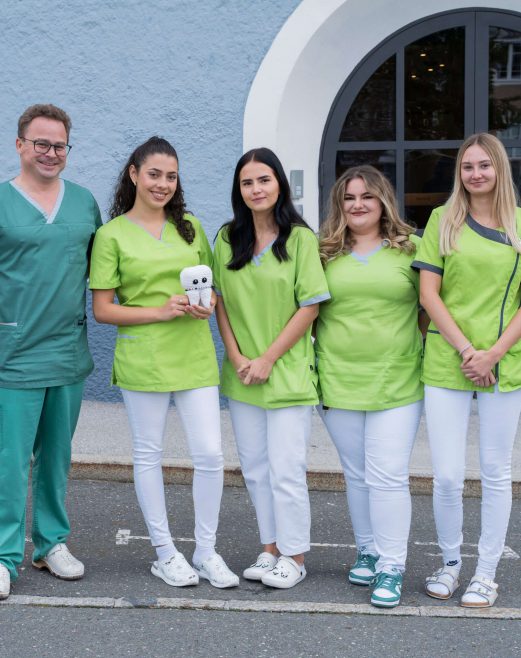 Team des Gesundheitszentrums Radstadt in grünen Arbeitskleidern vor der Praxis.